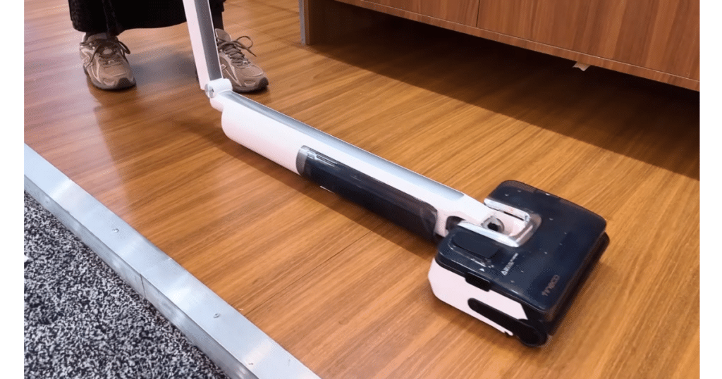 Tinco i7 Fold Cordless Hard Floor Cleaner at CES 2026 | Vacuum Wars Tineco Floor One i7 Fold wet-dry vacuum lying flat under furniture during a CES demonstration.