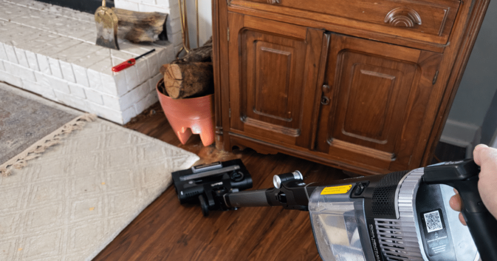 Vacuuming around firewood next to a fireplace.