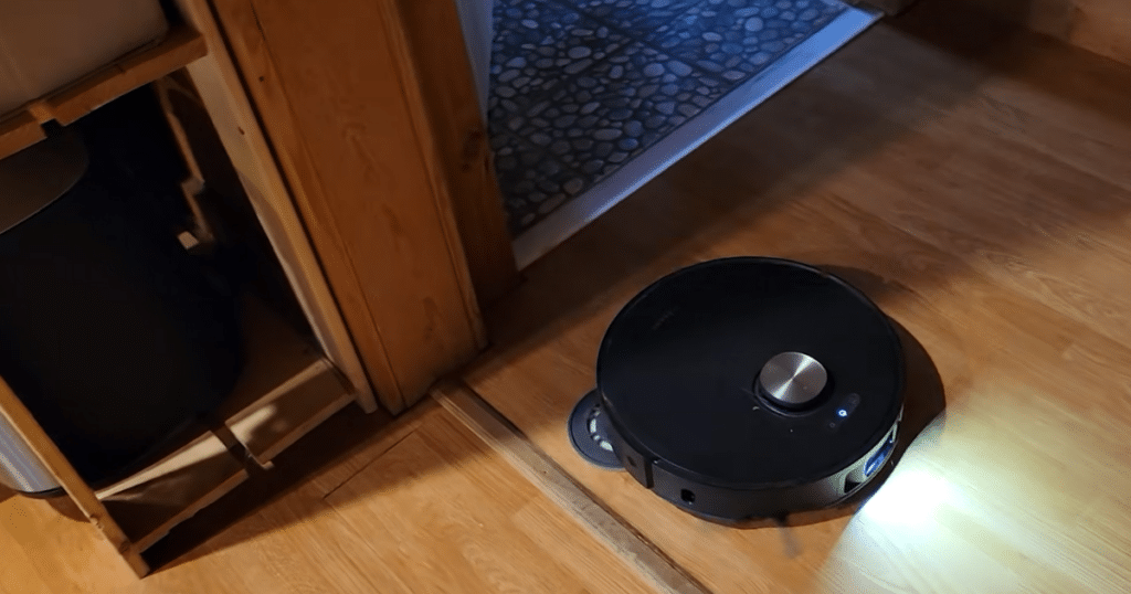 Dreame L50 Ultra Update hard floor | Vacuum Wars Dreame L50 Ultra robot vacuum cleaning hardwood floors near a doorway threshold, demonstrating suction power and edge cleaning performance.