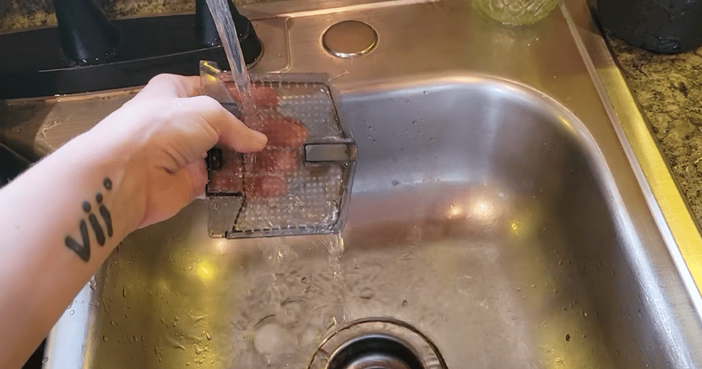 Dreame L50 Ultra Update tray | Vacuum Wars Cleaning the Dreame L50 Ultra dock washing tray insert under running water at a kitchen sink for routine maintenance.