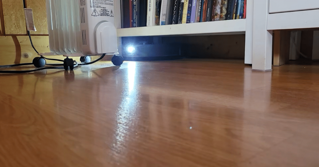 Dreame L50 Ultra Update under furniture | Vacuum Wars Dreame L50 Ultra robot vacuum cleaning under low furniture with LED light on hardwood floors in AI CleanGenius mode.