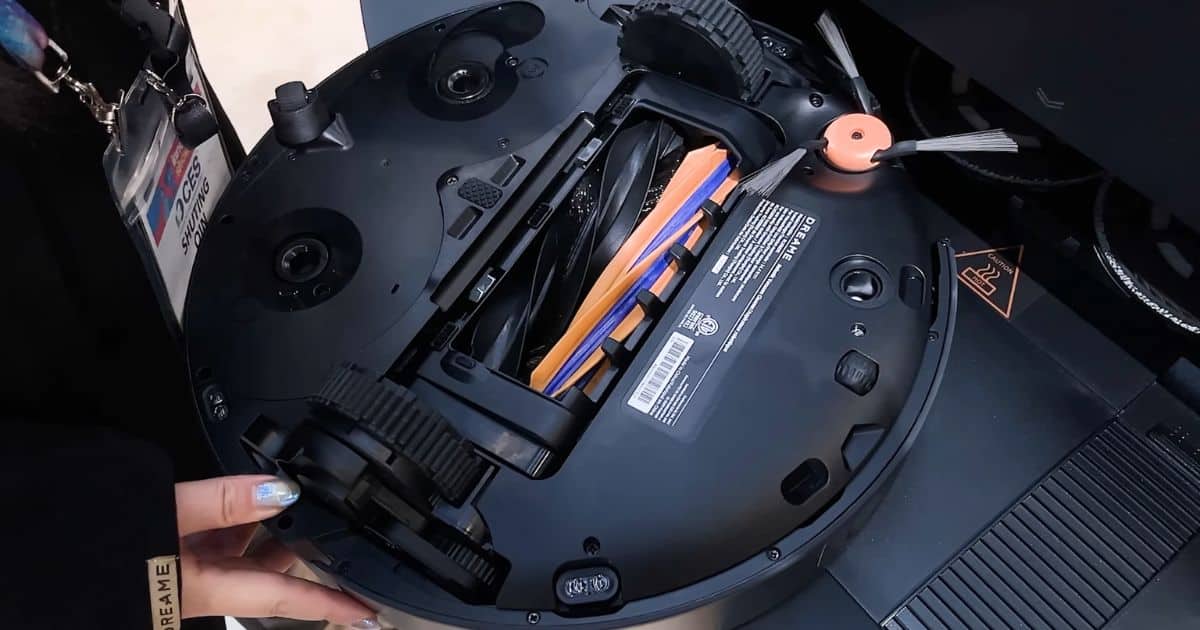 | Vacuum Wars Underside view of the Dreame X60 Max Ultra Complete robot vacuum showing the dual roller brush assembly and side brush during a hands-on demo.