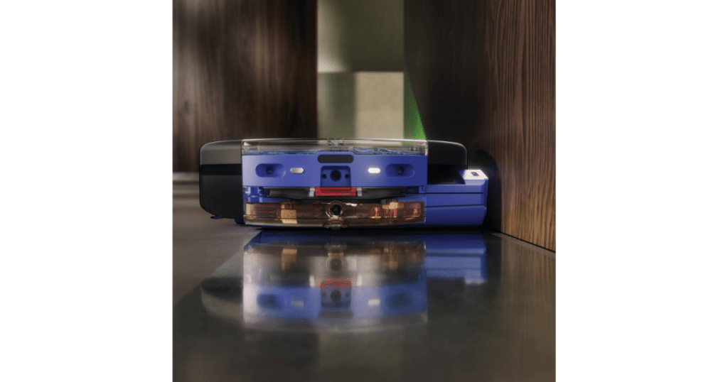 Dyson Spot and Scrub Wall Edge | Vacuum Wars Dyson Spot+Scrub AI robot vacuum cleaning along a wall with its wet roller extended toward the edge of the floor.