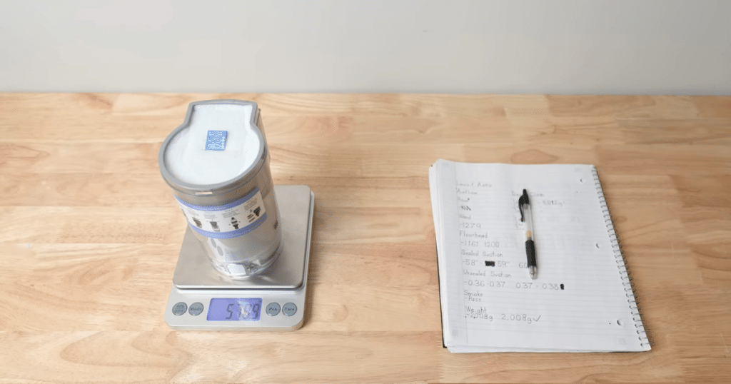 Levoit Aero carpet test weigh | Vacuum Wars Levoit Aero vacuum bin weighed on scale during deep carpet cleaning test with sand measurement