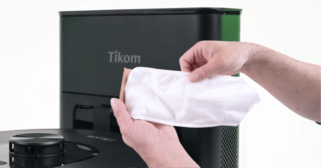 Tikom L8000 dock and bag | Vacuum Wars Hand holding the disposable dust bag used in the Tikom L8000 Plus auto-empty base station.