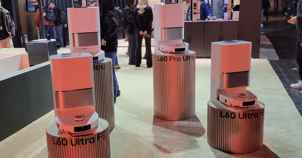 Several L60 Ultra Pro robots displayed on ribbed circular pedestals at a tech expo, with people in the background.
