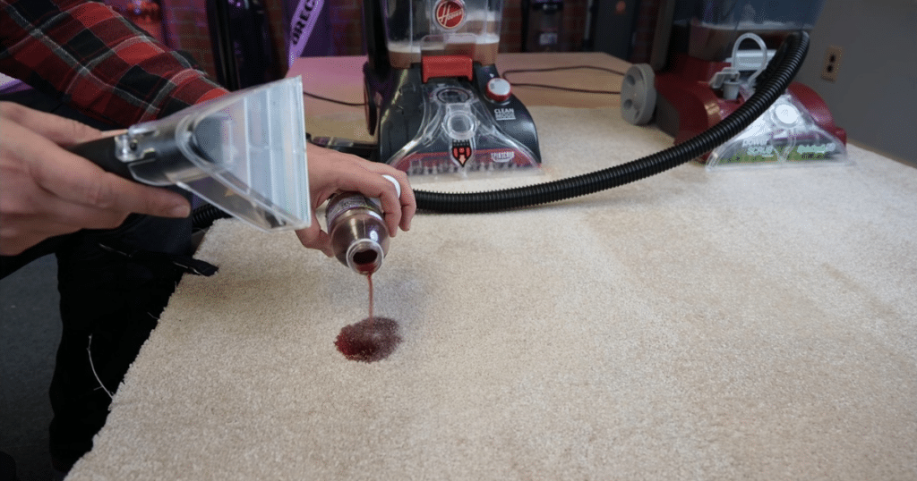 Hoover PowerScrub Deluxe Carpet Spot Stain Testing1 | Vacuum Wars Pouring grape juice on a carpet with the Hoover PowerScrub Deluxe in the background