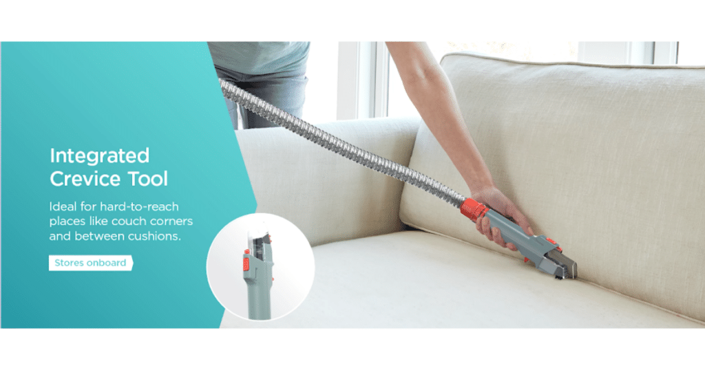 Shark CarpetXpert Integrated Crevice Tool | Vacuum Wars A person using the Shark EX151 CarpetXpert’s integrated crevice tool to clean between couch cushions, with the hose extended for reach.
