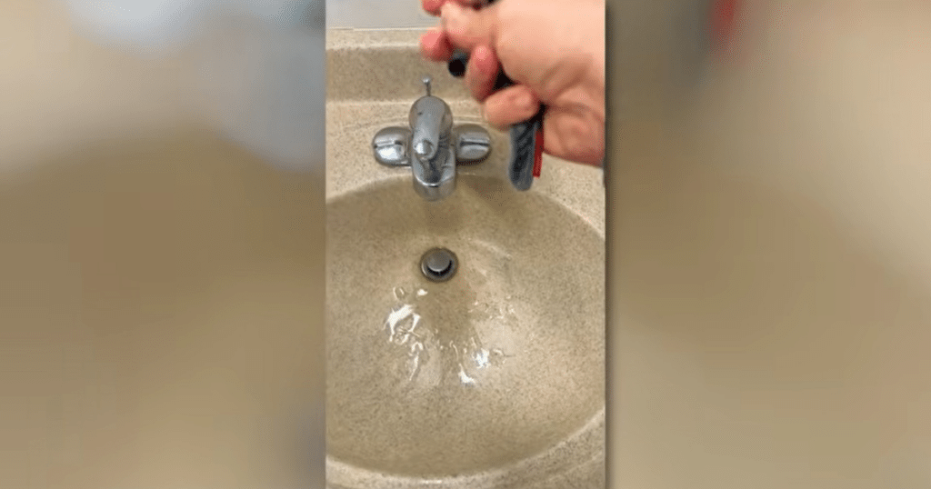 Shark Powerdetect UV Reveal wring | Vacuum Wars Hand wringing out water from a saturated flat mop pad over a sink, showing excess moisture buildup during cleaning.