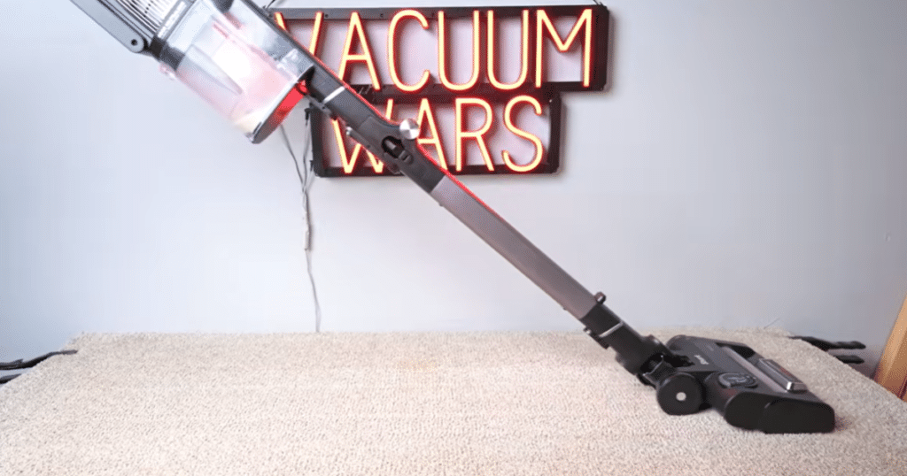 Shark Stratos Carpet Deep Clean Test | Vacuum Wars Shark Stratos cordless vacuum cleaning carpet with Vacuum Wars sign in the background.