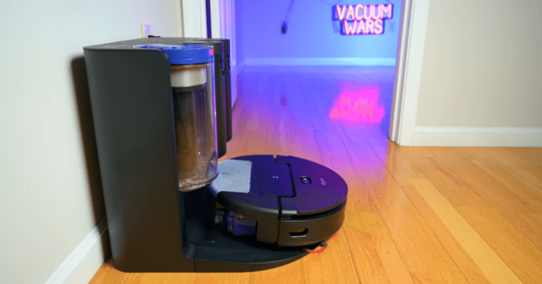 Dyson Spot+Scrub AI robot vacuum docked at its bagless auto-empty station on hardwood floor
