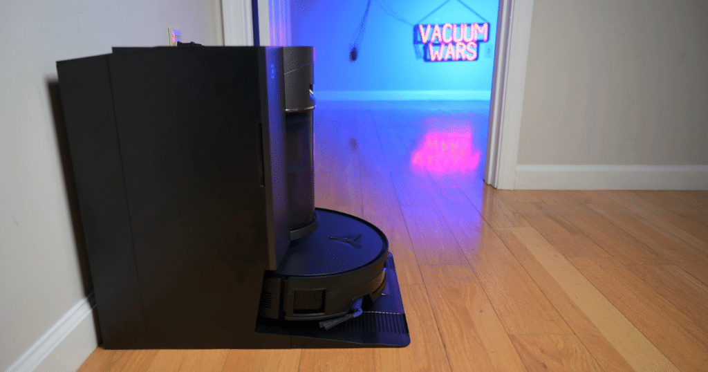 Ecovacs Deebot X12 OmniCyclone at our studio | Vacuum Wars Ecovacs Deebot X12 OmniCyclone robot vacuum docked at its bagless auto-empty station with roller mop system visible.