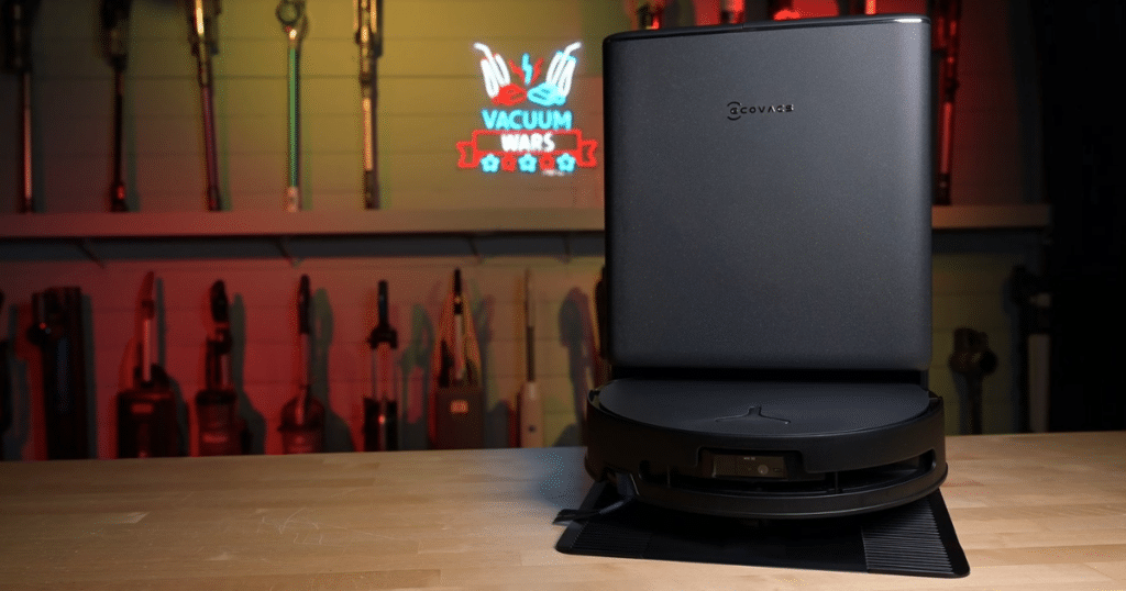 Ecovacs T90 at Vacuum Wars | Vacuum Wars The Ecovacs Deebot T90 Pro Omni robot vacuum and docking station positioned on a tabletop in the Vacuum Wars studio.