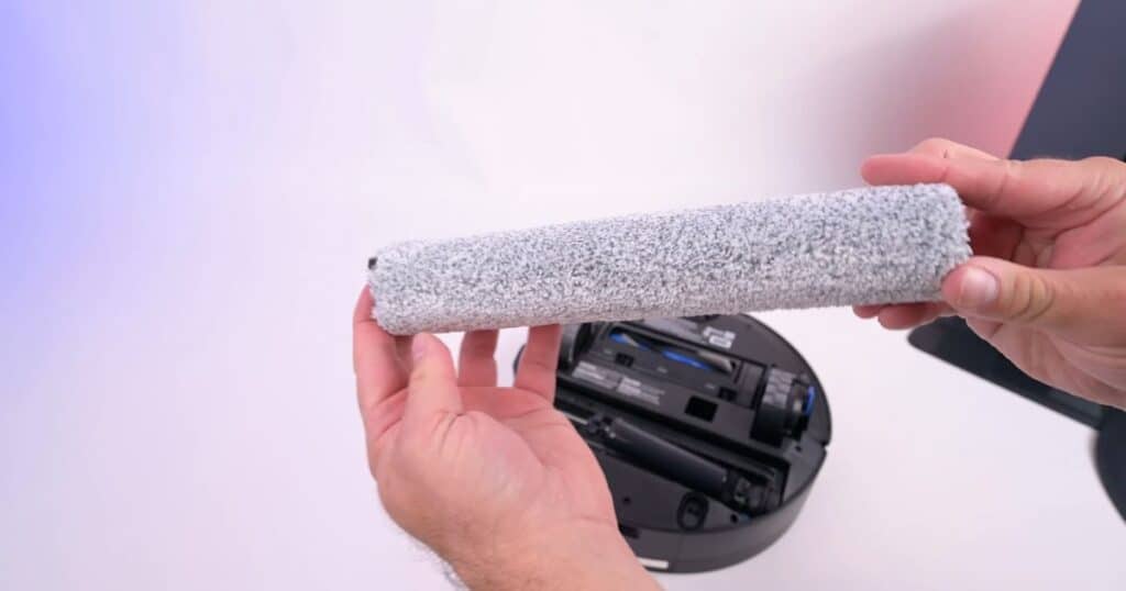 | Vacuum Wars Ecovacs X12 OmniCyclone Ozmo 3.0 roller mop being held above the underside of the robot vacuum.
