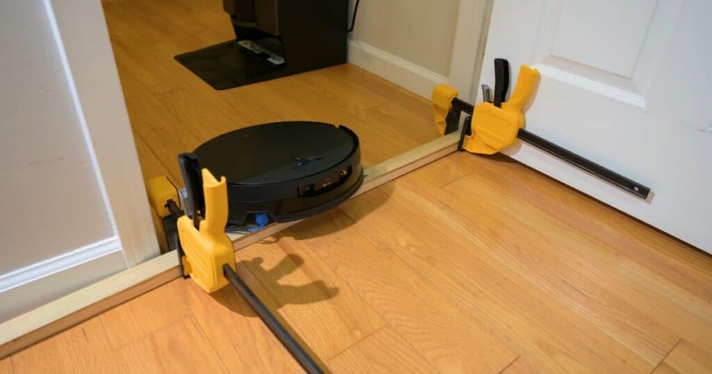 | Vacuum Wars Ecovacs X12 OmniCyclone robot vacuum crossing a raised doorway threshold during a threshold climbing test.