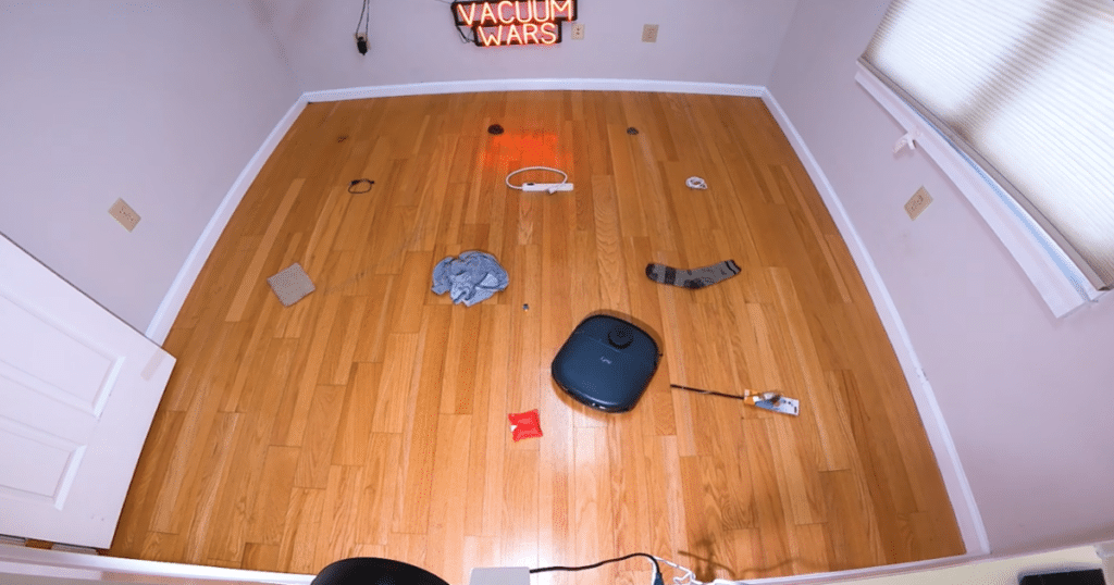 Eufy C28 Obstacle Avoidance | Vacuum Wars The Eufy Omni C28 robot vacuum navigating through an obstacle avoidance test area with common household objects placed across a hardwood floor.