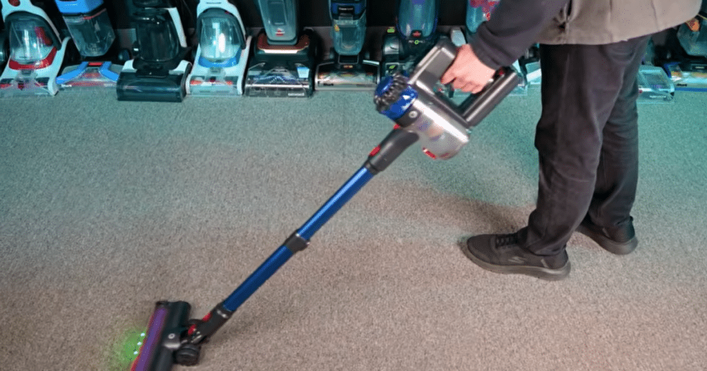 KARDV V06 weight | Vacuum Wars The KARDV V06 cordless vacuum being used on carpet during Vacuum Wars testing, highlighting its lightweight 1,386-gram handle weight compared to the Tikom V500 at 1,547 grams and the cordless vacuum average of 1,511.8 grams.