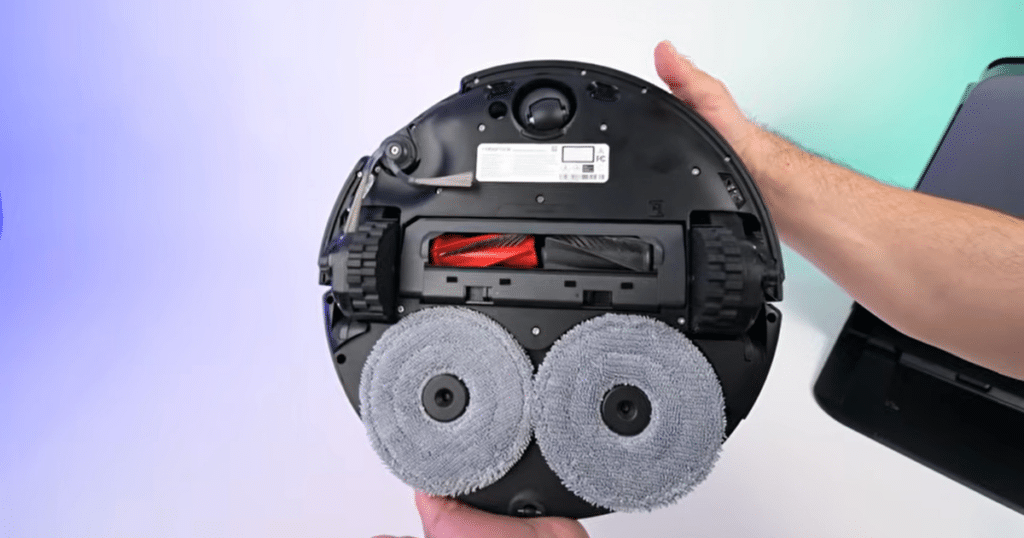 Roborock Saros 20 underside | Vacuum Wars Underside of the Roborock Saros 20 robot vacuum showing dual spinning mop pads, main brush, and wheel system. The Saros 20 uses dual mop pads spinning at 200 RPM with adaptive mopping pressure up to 13 newtons for improved floor cleaning performance.