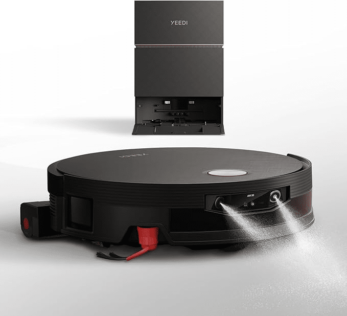 image | Vacuum Wars Yeedi robotic vacuum on the floor with its tall charging dock in the background; the vacuum has red side brushes and a front spray for mopping as it cleans.