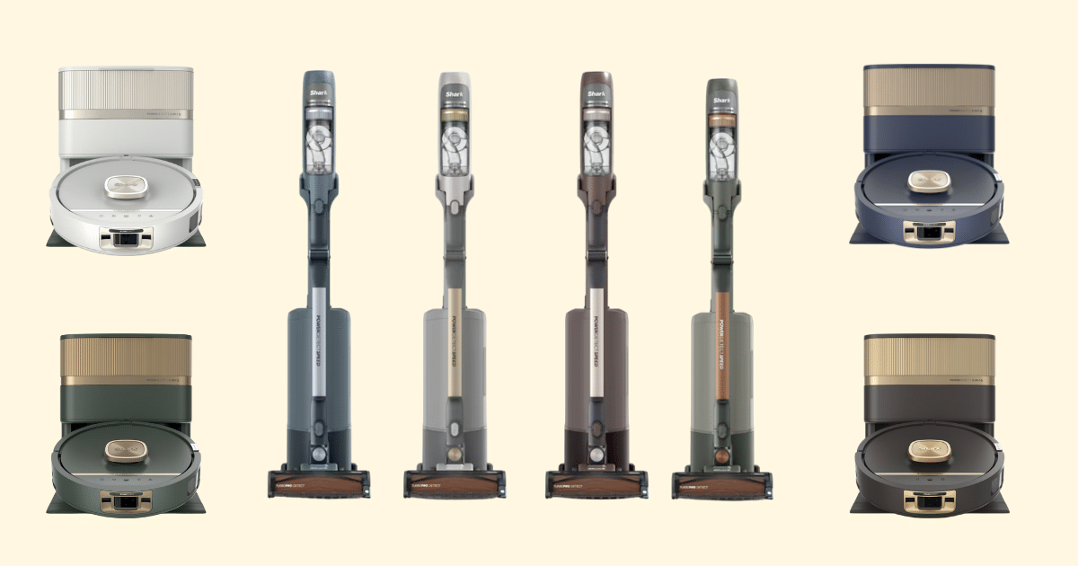 Row of Shark vacuum cleaners in various colors on a pale yellow background, including two dock stations at each end and four vertical stick vacuums in the center.