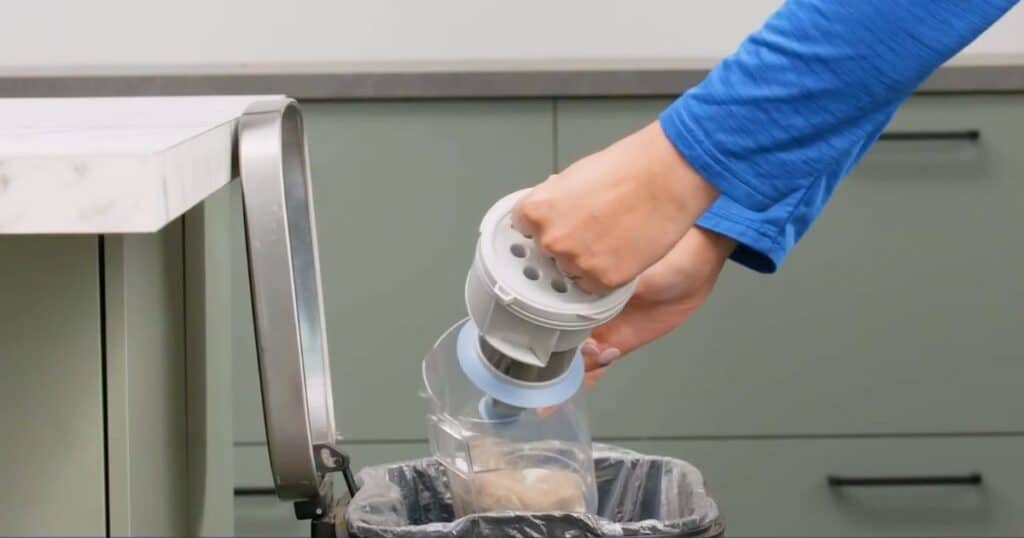 | Vacuum Wars Bissell PowerClean 4173 dustbin being removed and emptied into a trash can.