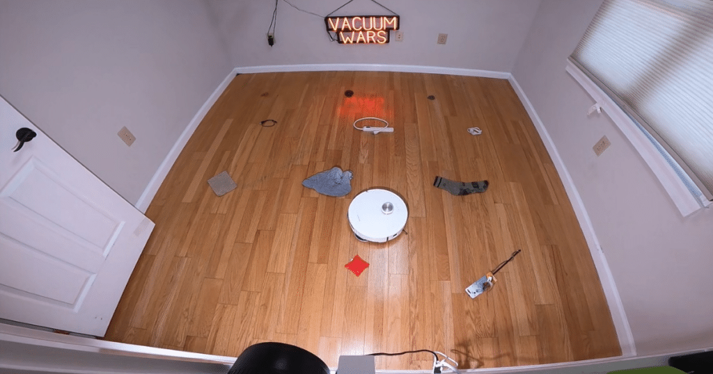 Dreame L60 Ultra PE Obstacle Avoidance Test at the Vacuum Wars studio | Vacuum Wars Dreame L60 Ultra PE navigating Vacuum Wars’ obstacle avoidance test course with household objects on a hardwood floor