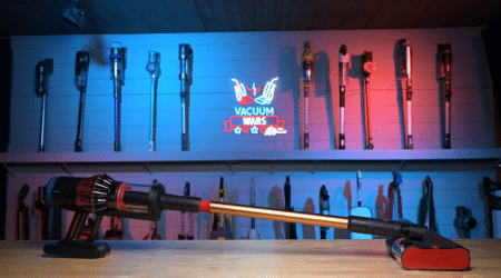Dyson V16 Piston Animal Submarine in studio 450 | Vacuum Wars Row of vacuum attachments hanging on a blue-lit display wall, with a long vacuum wand resting on a bench in front.
