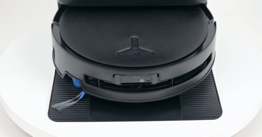 ECOVACS T80s Omni texture | Vacuum Wars Close-up front view of the ECOVACS Deebot T80s Omni robot vacuum showing its leather-textured top surface, front navigation sensors, and side brush while docked at the Omni base station.
