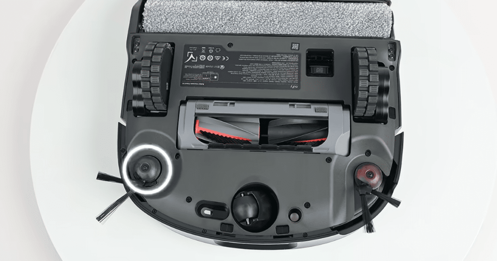 Eufy Omni S2 brush system | Vacuum Wars Underside of the Eufy Omni S2 robot vacuum showing its DuoSpiral split main brush, dual side brushes, and extending side brush arm. The anti-tangle brush design channels hair toward the suction port to reduce hair wrap.