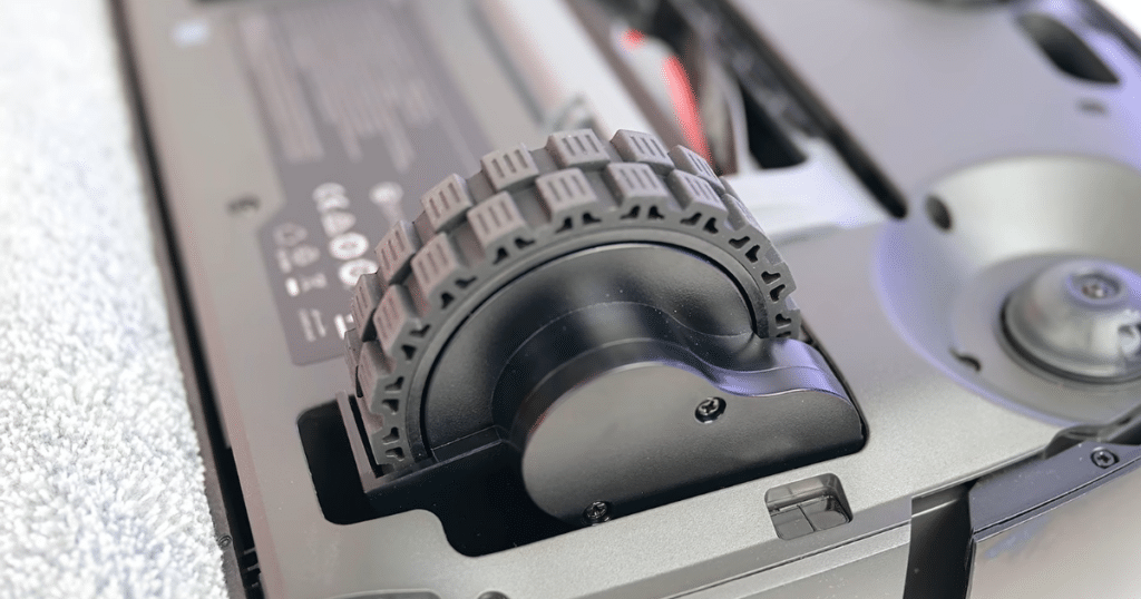 Eufy Omni S2 chassis lift | Vacuum Wars Close-up of the Eufy Omni S2's mechanical chassis lifting mechanism, which raises the robot to improve mobility on carpets. Eufy rates the system to drive onto carpets up to 2 inches thick.