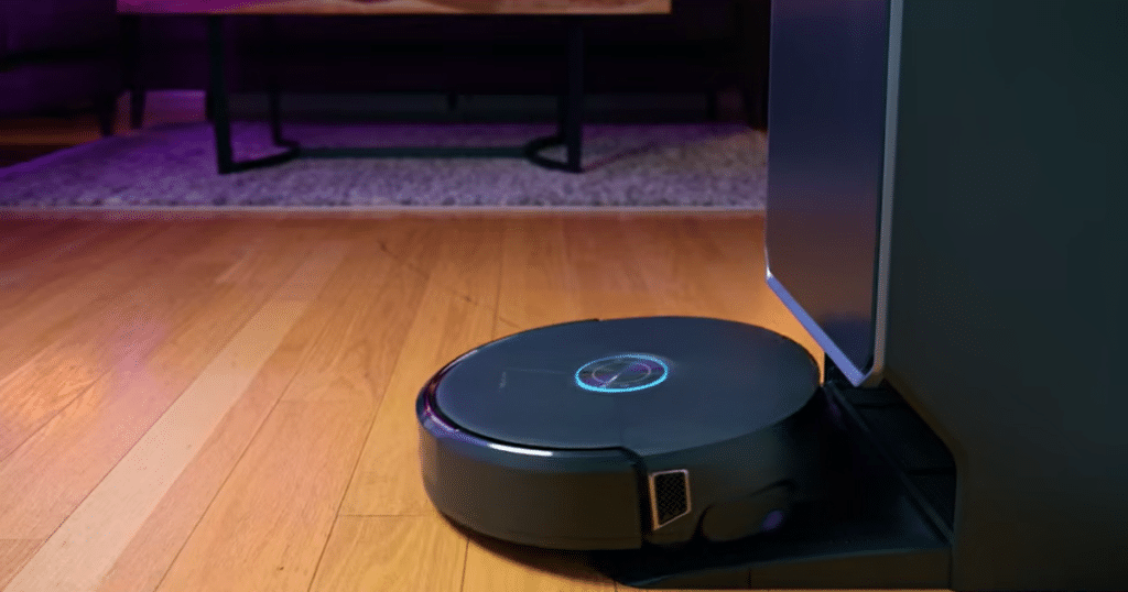Narwal Flow 2 studio | Vacuum Wars Narwal Flow 2 robot vacuum docked at its base station on a hardwood floor, highlighting the self-cleaning dock and the robot's updated design following firmware improvements that enhanced real-world cleaning performance.