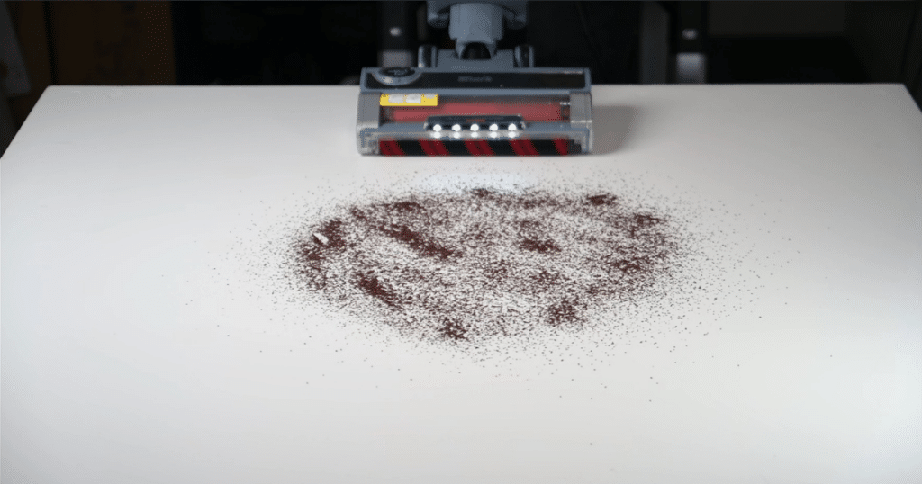 The Shark Performance Powered Lift-Away upright vacuum approaching fine debris on a hard floor