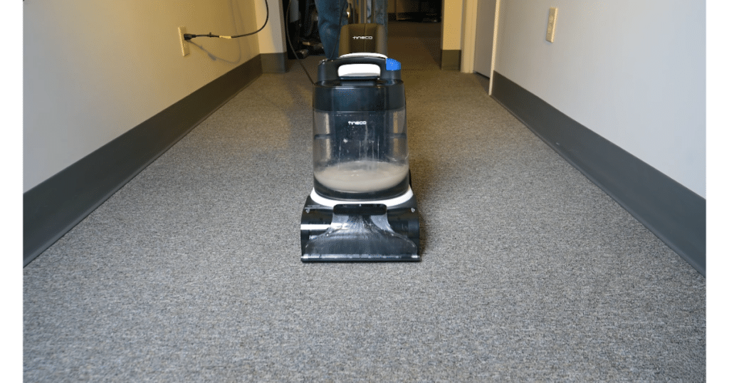 Tineco Carpet ONE Cruiser in Use at the Vacuum Wars Studio | Vacuum Wars Tineco Carpet ONE Cruiser carpet cleaner being used on a carpeted hallway, with cleaning solution visible in the recovery tank.