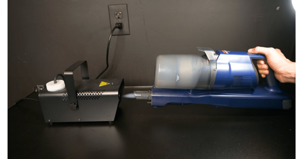 Bissell PowerClean DualBrush Cordless Vacuum filtration Test at Vacuum Wars | Vacuum Wars Bissell PowerClean DualBrush handheld unit connected to Vacuum Wars’ fog-testing equipment during a filtration evaluation.