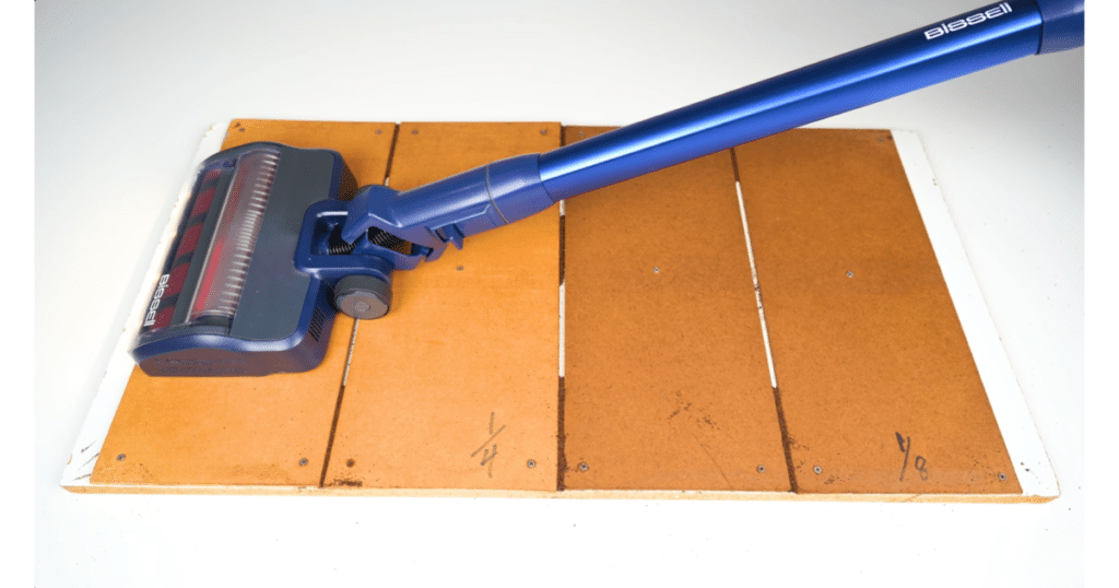 Bissell PowerClean DualBrush Crevice pickup test at Vacuum Wars | Vacuum Wars Bissell PowerClean DualBrush cordless vacuum positioned on a hard-floor crevice test surface with multiple recessed seams.