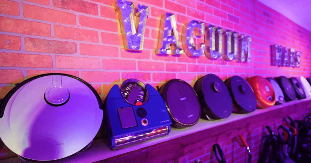 Vacuum Wars Studio Robots Shelf | Vacuum Wars Robot vacuums displayed on a shelf at the Vacuum Wars testing studio illustrate the types of connected cleaning robots that could be affected by future FCC authorization restrictions.