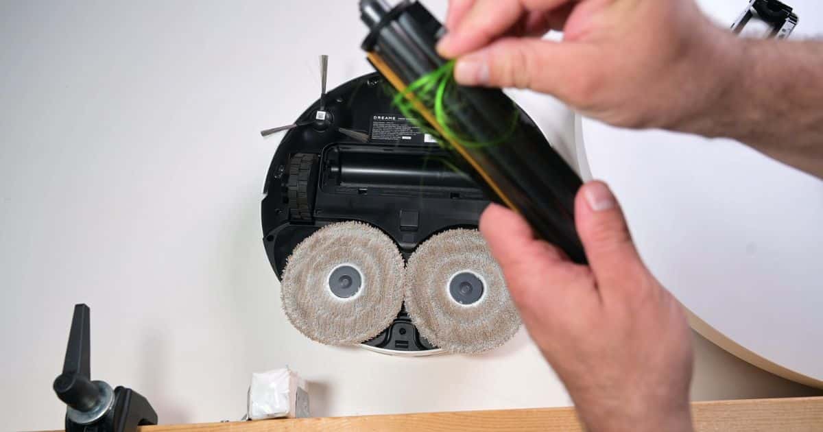 | Vacuum Wars Dreame D30 Ultra TriCut main brush removed from the robot vacuum with long hair wrapped around the roller.