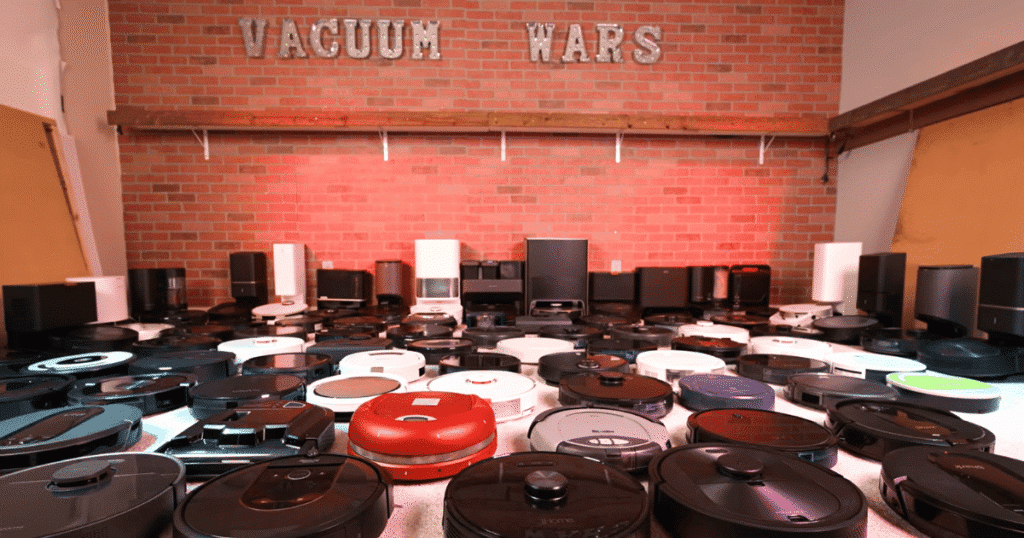 vacuum wars studio robots brick wall | Vacuum Wars Rows of robot vacuums and self-emptying docks in the Vacuum Wars test lab represent the complex supply chains behind modern consumer robotics.