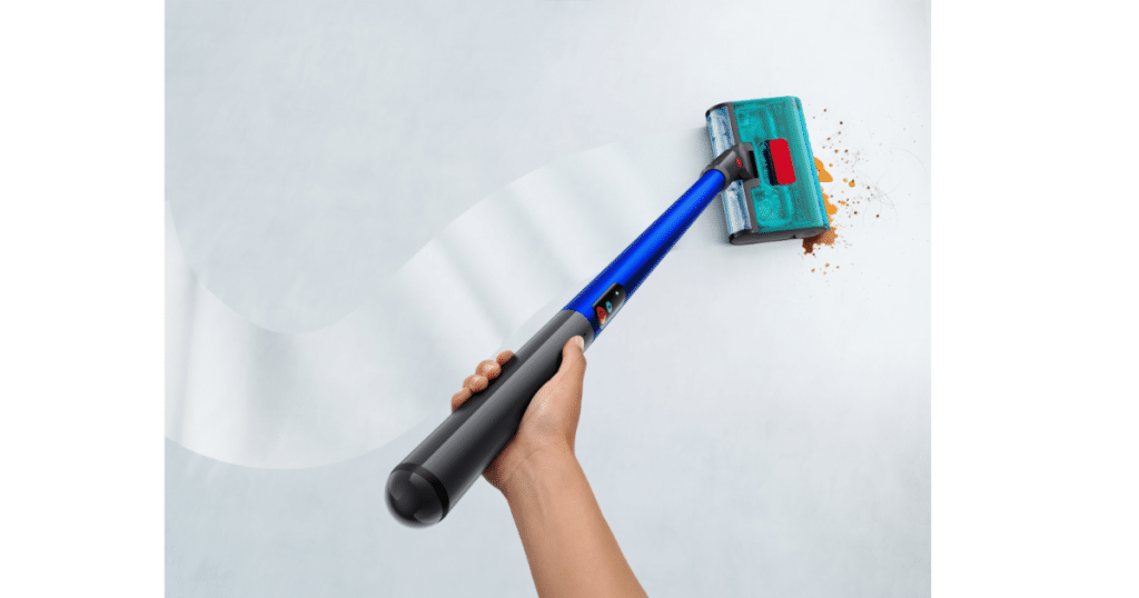 Dyson W1 PencilWash | Vacuum Wars Overhead view of a person using the Dyson W1 PencilWash wet floor cleaner to collect scattered debris from a light-colored floor.