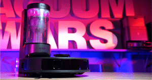 Eureka E20 Evo Plus Robot Vacuum at the Vacuum Wars Studio After Testing | Vacuum Wars Eureka E20 Evo Plus Robot Vacuum on a table under neon pink/purple lighting with large bold letters in the background
