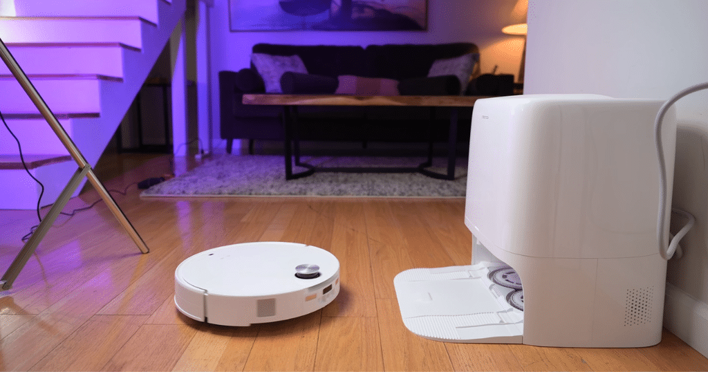 Roborock Qrevo Edge 3 Pro robot vacuum product testing at Vacuum Wars | Vacuum Wars White Roborock Qrevo Edge 3 Pro robot vacuum positioned beside its multifunctional dock on hardwood flooring in the Vacuum Wars studio.