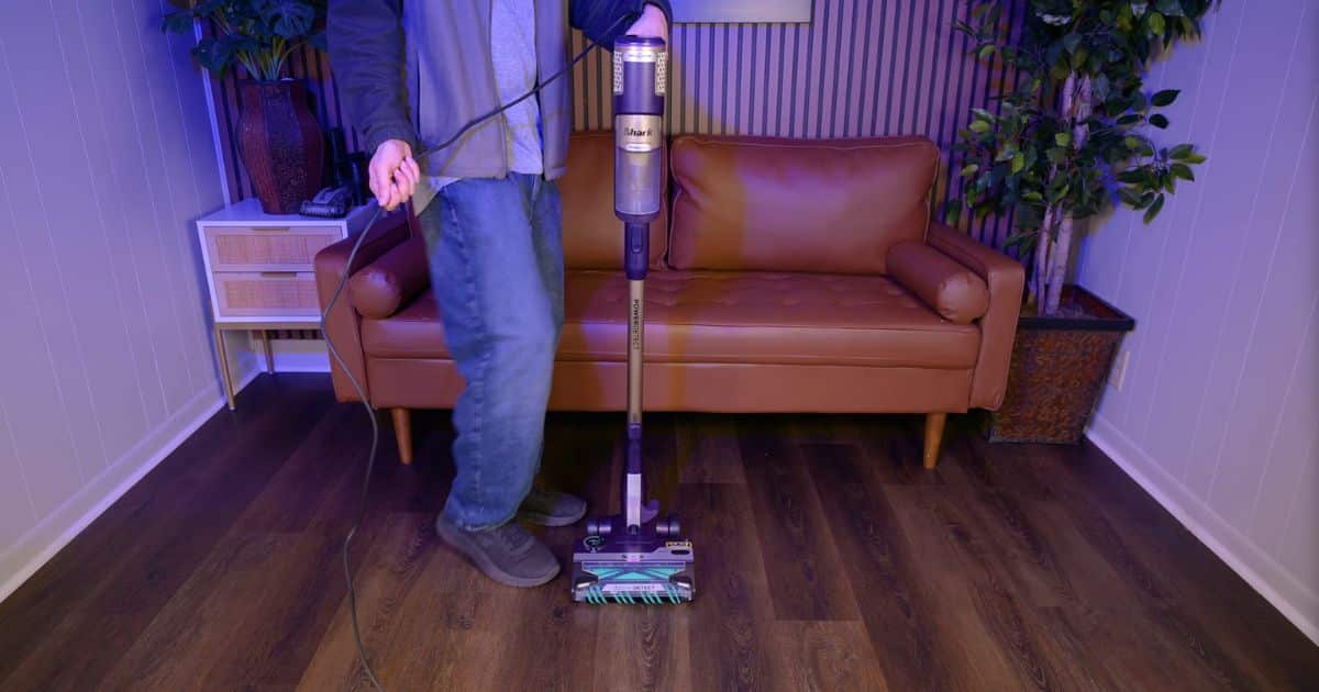 | Vacuum Wars Shark PowerDetect Ultra-Light HZ4002 corded stick vacuum being used on a hard floor while the user manages the power cord.