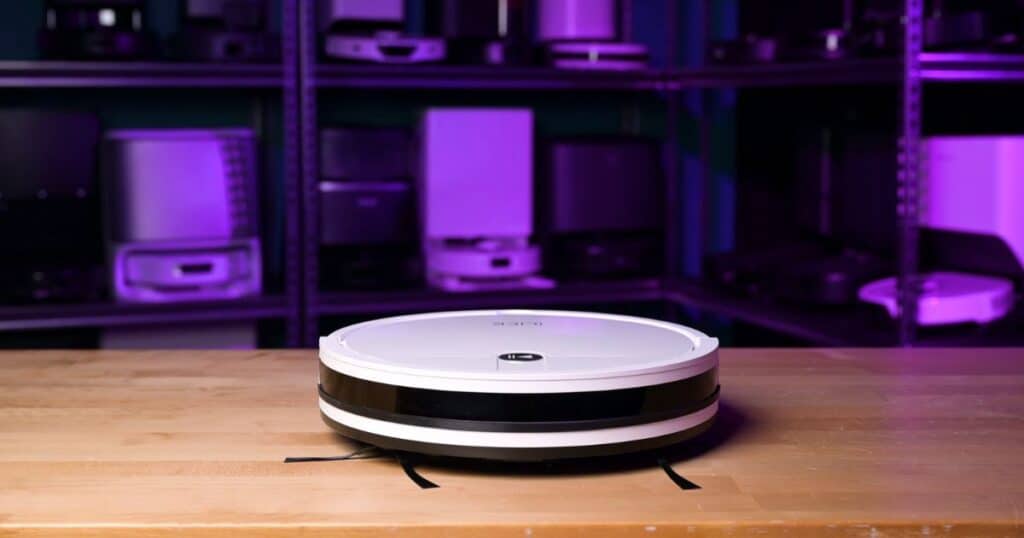 | Vacuum Wars ILIFE V2 robot vacuum on a wooden table in the Vacuum Wars testing studio.