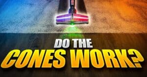 | Vacuum Wars Dyson V10 Konical cleaner head positioned between carpet and hard flooring, with green floor illumination. Large yellow and white text reads “DO THE CONES WORK?”