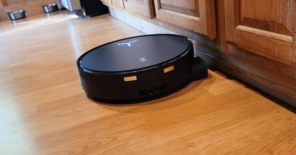 Ecovacs X12 Mopping User Review Vacuum Wars | Vacuum Wars Ecovacs X12 OmniCyclone robot vacuum cleaning a wood-look kitchen floor alongside wooden cabinets.